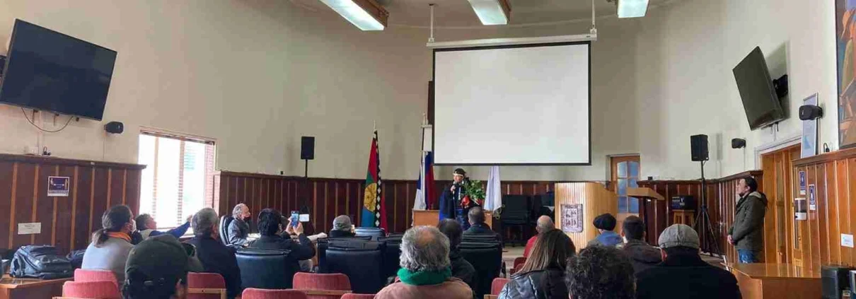 Lamuen Margarita Milanca al cierre del Encuentro Medioambiental de la Provincia de Llanquihue. Está en el salón municipal y un grupo de personas, sentadas en silla, la escucha.