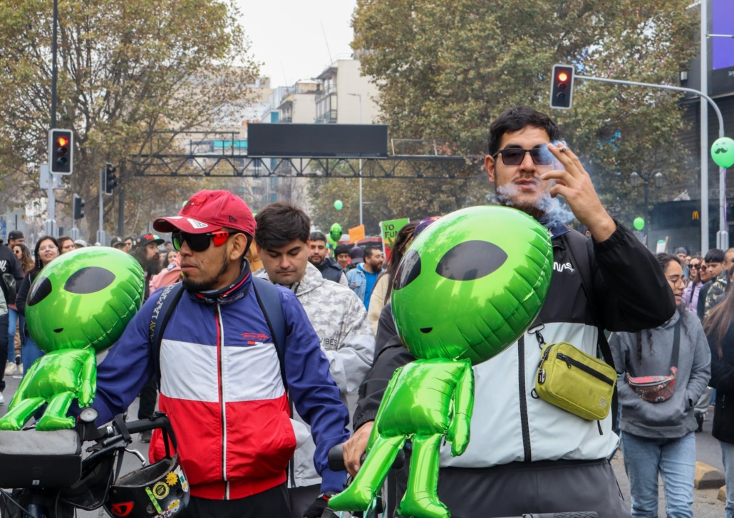 dos asistentes a la marcha sosteniendo un marciano cada uno mientras fuman 